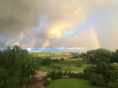 a rainbow in the sky over a field at Comfortable apartments - Nature, silence, coziness in Kėdainiai