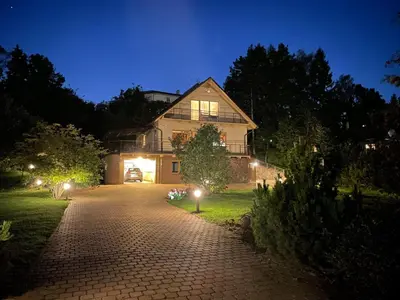 a house at night with lights on a driveway at Comfortable apartments - Nature, silence, coziness in Kėdainiai