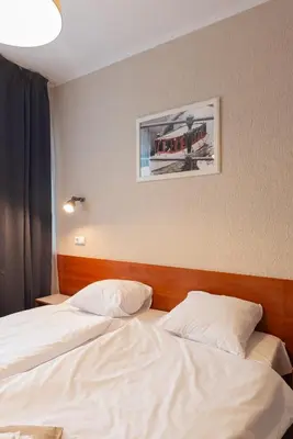 a bedroom with two beds and a picture on the wall at Inza Guest House in Druskininkai