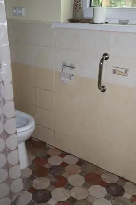 a bathroom with a toilet and a tile floor at Sveikatinimas kaime in Vilkaviškis