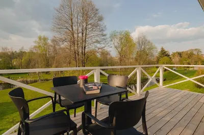 a patio with a table and chairs on a deck at Gandro lizdas in Lekėčiai
