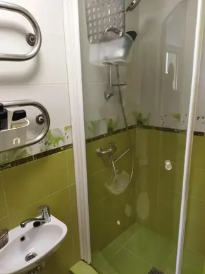 a green bathroom with a shower and a sink at Itaja Apartment 91 in Šiauliai