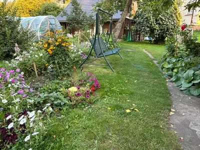 a garden with flowers and a swing in the grass at RYTO GARSAI in Merkinė