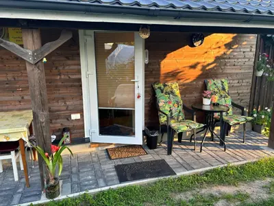 a patio with two chairs and a table in front of a house at RYTO GARSAI in Merkinė