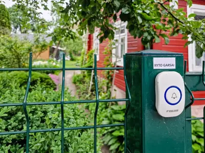 a green trash can in front of a fence at RYTO GARSAI in Merkinė