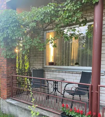 a balcony with a table and chairs on a house at Petro Apartamentai in Kačerginė