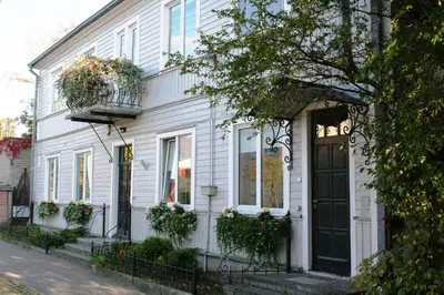 a white house with a black door on a street at KaunasInn in Kaunas