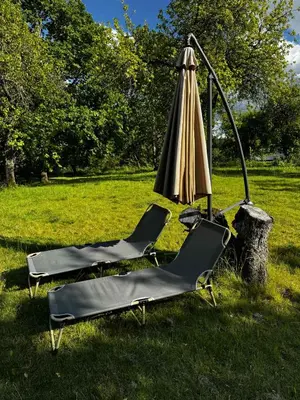 an umbrella and two lounge chairs in the grass at Obuoliu Sala OLAGA on the Apple Island in Gaylyunay
