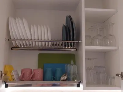 a kitchen shelf with plates and bowls and glasses at DIVA contactless check in & out in Šiauliai