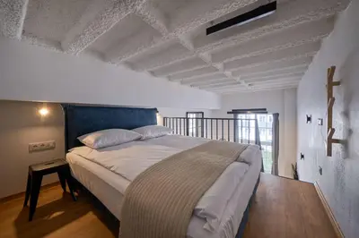 a bedroom with a large bed with a cross on the wall at Queen Barbora Central Lofts in Kaunas