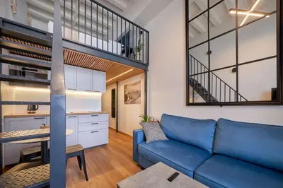 a living room with a blue couch and a loft at Queen Barbora Central Lofts in Kaunas