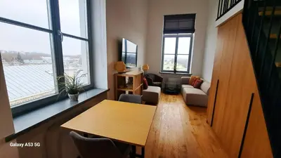 a living room with a table and some windows at KaunasInn - AM in Kaunas
