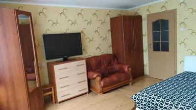 a bedroom with a television and a leather chair at Visaginas Taikos 84 in Visaginas
