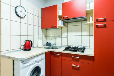 a kitchen with red cabinets and a washing machine at Juozapaviciaus apartment in Kaunas