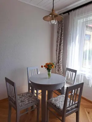 a dining room table and chairs with a vase of flowers on it at Vasarnamis Zarasuose - Vyšnia in Zarasai