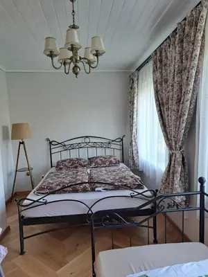 a bedroom with a bed and a chandelier at Vasarnamis Zarasuose - Vyšnia in Zarasai