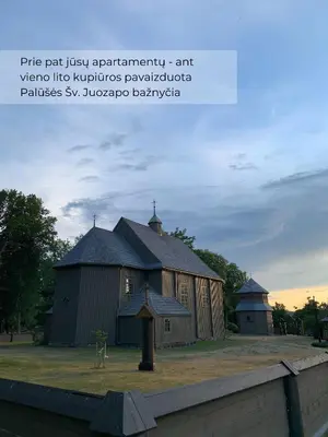 a large barn with a tower and a church at Palūšės Apartment in Palūšė