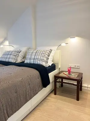 a bedroom with a bed with a table next to it at NERIS Apartments in Vilnius