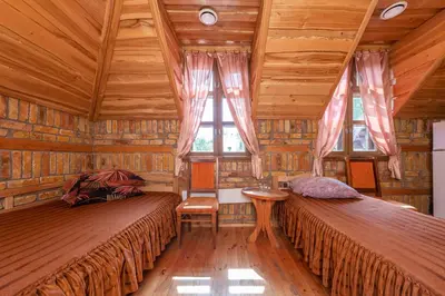 two beds in a room with wooden ceilings and windows at Meškiai in Meškiai