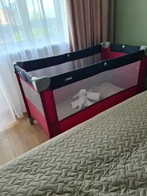 a baby crib with a teddy bear sitting on a bed at Samanų apartamentai in Šiauliai
