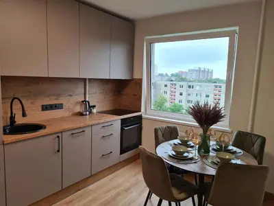 a kitchen with a table and a large window at Samanų apartamentai in Šiauliai