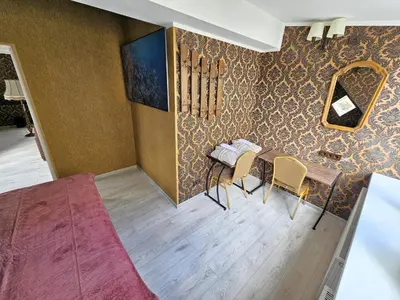 a room with a table and chairs against a wall at Square apartments in Rokiškis