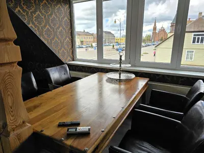 a wooden table in a room with chairs and windows at Square apartments in Rokiškis