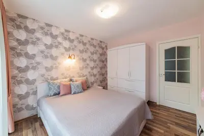a bedroom with a bed and a wall with flowers at A.P. Apartment in Šiauliai