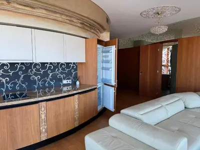 a living room with a white couch and a kitchen at Helios Extra Apartment in Vilnius skyscraper 20 floor in Vilnius