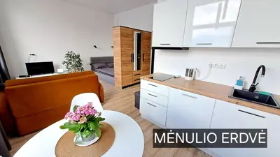 a kitchen and a living room with a table and flowers at Mano erdvės in Anykščiai