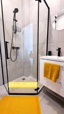 a bathroom with a shower with a yellow rug at Mano erdvės in Anykščiai