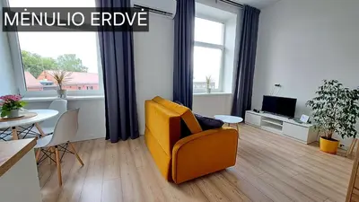 a living room with a yellow chair and a table at Mano erdvės in Anykščiai
