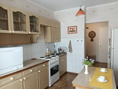 a kitchen with wooden cabinets and a stove top oven at Welcome home Taikos 72V-22 in Visaginas