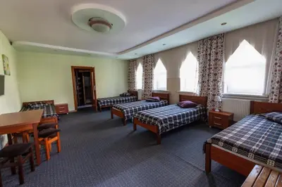 a hotel room with three beds and a table and chairs at Regina House in Kaunas