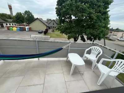 two white chairs and a hammock on a patio at Naisiai-2 in Naisiai