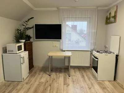 a kitchen with a television and a table and refrigerator at Naisiai-2 in Naisiai
