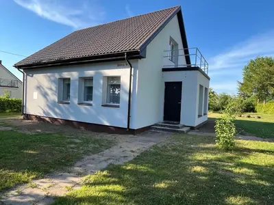 a small white house with a black door at Naisiai in Naisiai