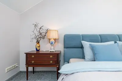 a bedroom with a blue bed and a nightstand with a lamp at Cozy apartments by the river near old town in Kaunas