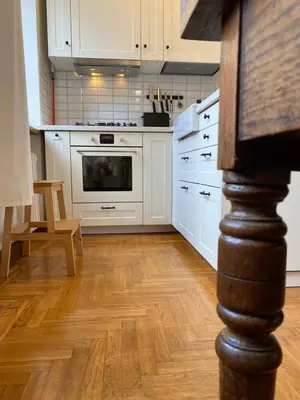 a kitchen with white cabinets and a wooden floor at Spacious Old Town Apt, 3 Rooms, Sleeps 6-7 in Kaunas