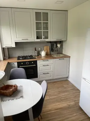 a kitchen with white cabinets and a table with chairs at Arena apartment in Panevėžys