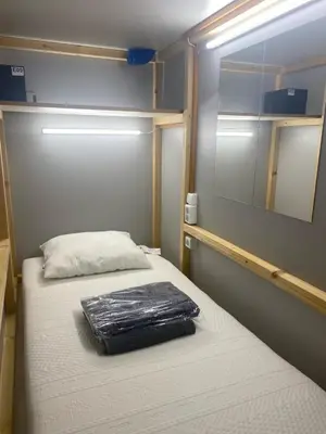 a small room with two beds and a mirror at Capsule Hostel Logistic Vilnius in Vilnius