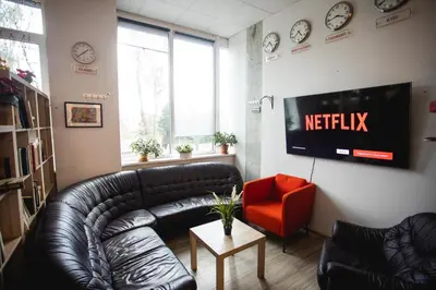a living room with a black leather couch and a red chair at Capsule Hostel Logistic Vilnius in Vilnius