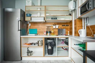 a kitchen with white shelves and a refrigerator at Capsule Hostel Logistic Vilnius in Vilnius