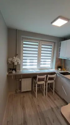 a kitchen with two chairs and a table and two windows at MEŠKUTĖS APARTAMENTAI in Druskininkai