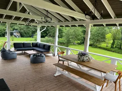 a porch with a couch and a table and chairs at Pirties namelis Paliekys in Lekėčiai