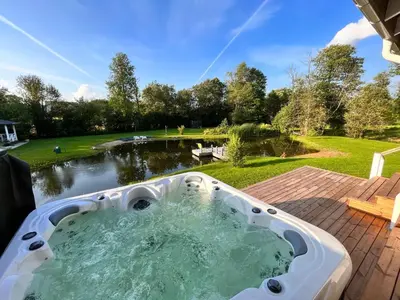 a jacuzzi tub on a patio next to a pond at Pirties namelis Paliekys in Lekėčiai