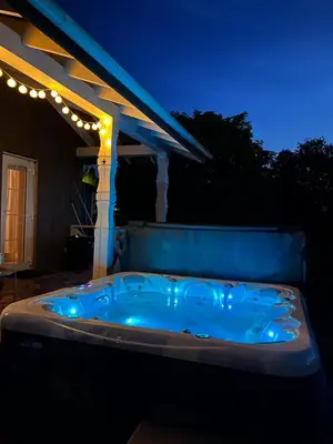 a jacuzzi tub sitting under a pergola at night at Pirties namelis Paliekys in Lekėčiai