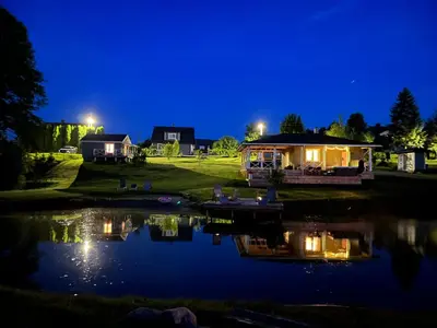 a night view of a house with a pond at Pirties namelis Paliekys in Lekėčiai