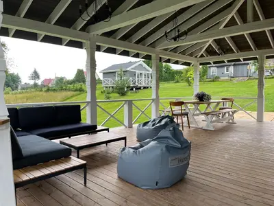 a covered porch with a couch and chairs and a table at Pirties namelis Paliekys in Lekėčiai