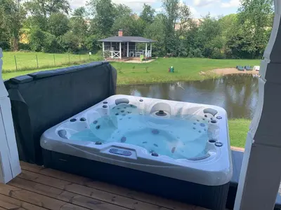a hot tub on a deck with a view of a lake at Pirties namelis Paliekys in Lekėčiai